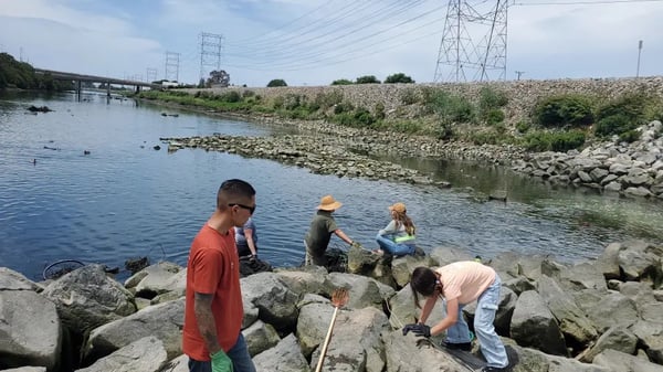 Four people on rock cleaning debris from river
