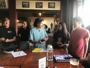 Two women and two men standing around a table at pub.