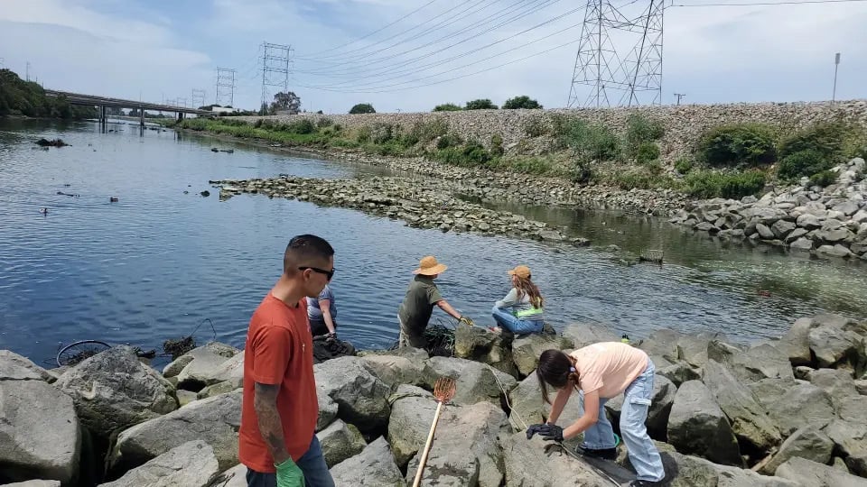 Four people on rock cleaning debris from river